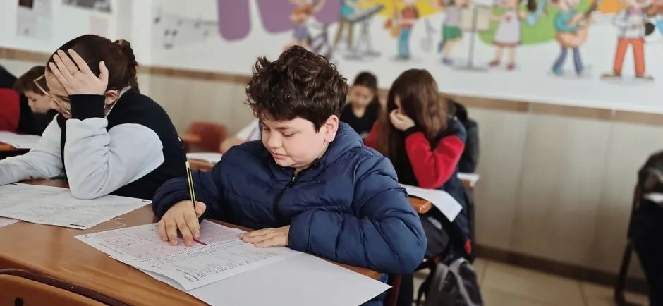 Un alumno de primaria rellenando una hoja de respuestas en un pupitre durante un examen estandarizado