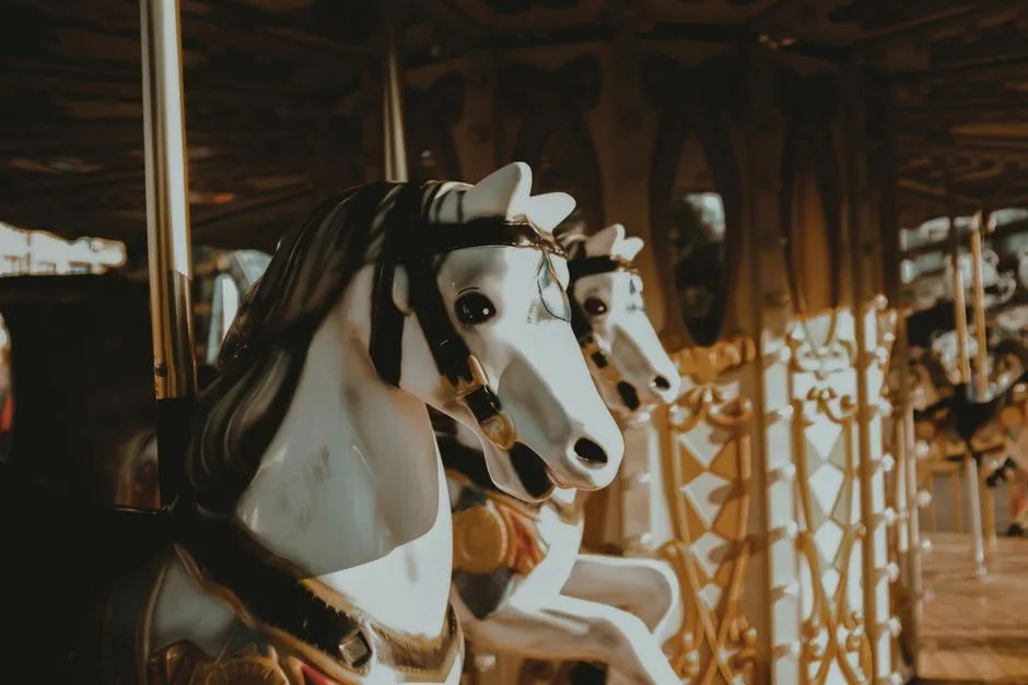 Siyah yeleli ve altın işlemeli, vintage bir lunapark atlıkarıncasında sıralanmış süslü beyaz atlıkarınca atlarının yakın çekimi