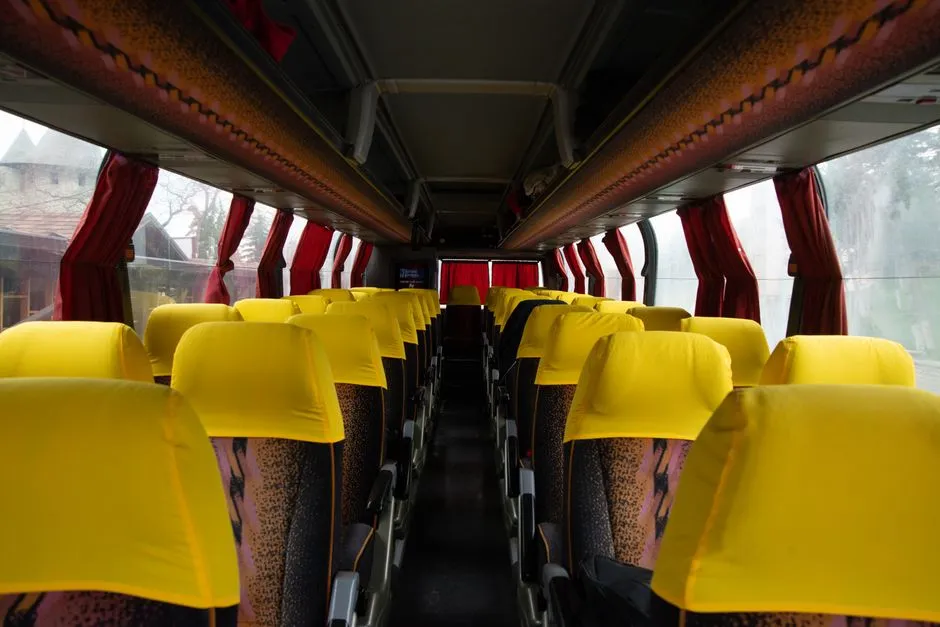Reihen leerer Reisebussitze mit gelben Kopfstützen, Blick den Mittelgang hinunter, keine Personen sichtbar