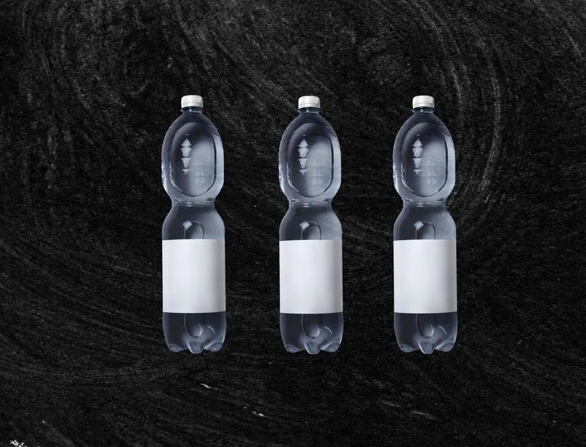 Drei identische Plastikflaschen mit leeren weißen Etiketten nebeneinander stehend, die Art Einwegbehälter, die über Deutschlands Pfandsystem zurückgegeben wird
