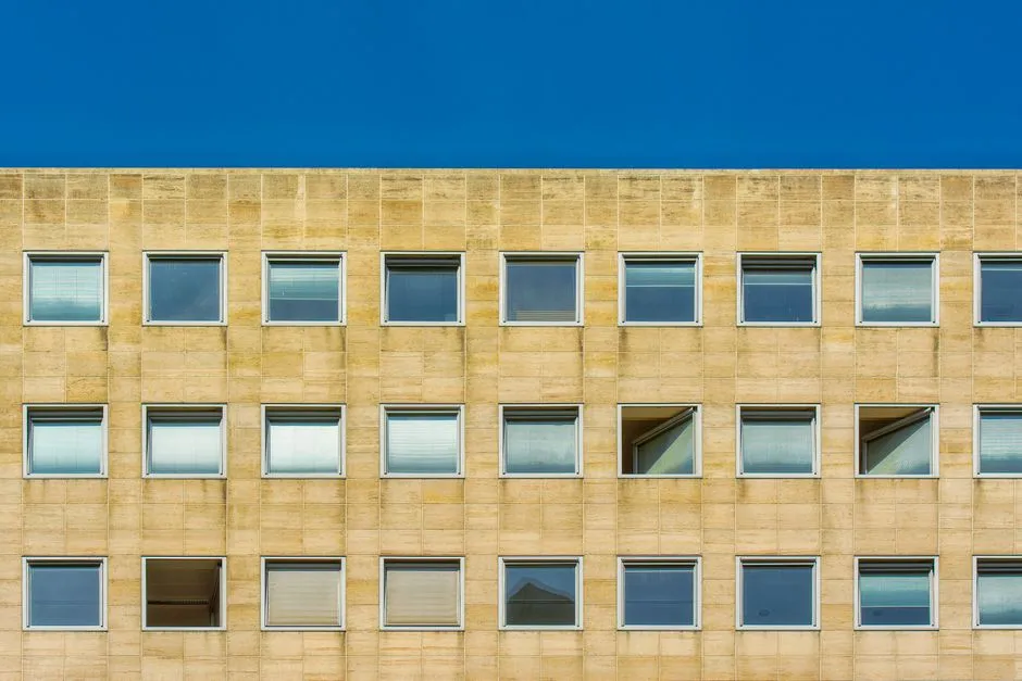 Die Fassade eines modernen Bürogebäudes mit Reihen quadratischer Fenster vor klarem blauem Himmel