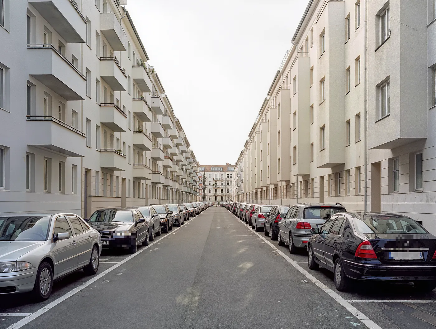 Eine lange Berliner Wohnstraße mit Stoßstange an Stoßstange geparkten Autos entlang markierter Bewohnerparkplätze, beidseitig Reihen von Altbau-Wohnhäusern