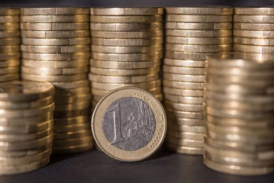 Primer plano de monedas de un euro y de pequeña denominación apiladas sobre una superficie oscura