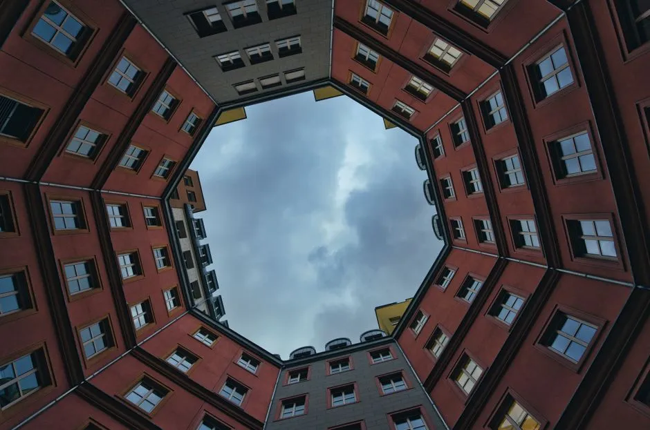 Symmetrischer Blick von unten in einen Berliner Wohnhof, Fassaden mit Fensterreihen umschließen eine zentrale Öffnung zum Himmel