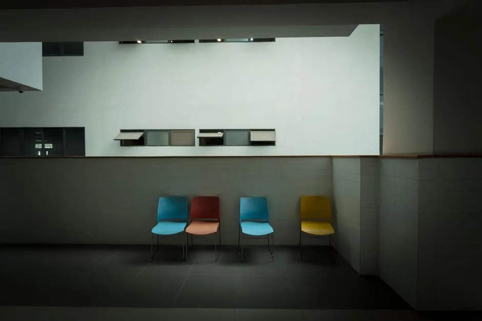 Una sala de espera tranquila y vacía de estilo hospitalario moderno con sillas de colores, sin personas visibles