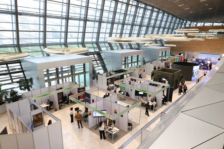 Eine belebte moderne Messehalle mit Besuchern, die sich zwischen den Ständen bewegen