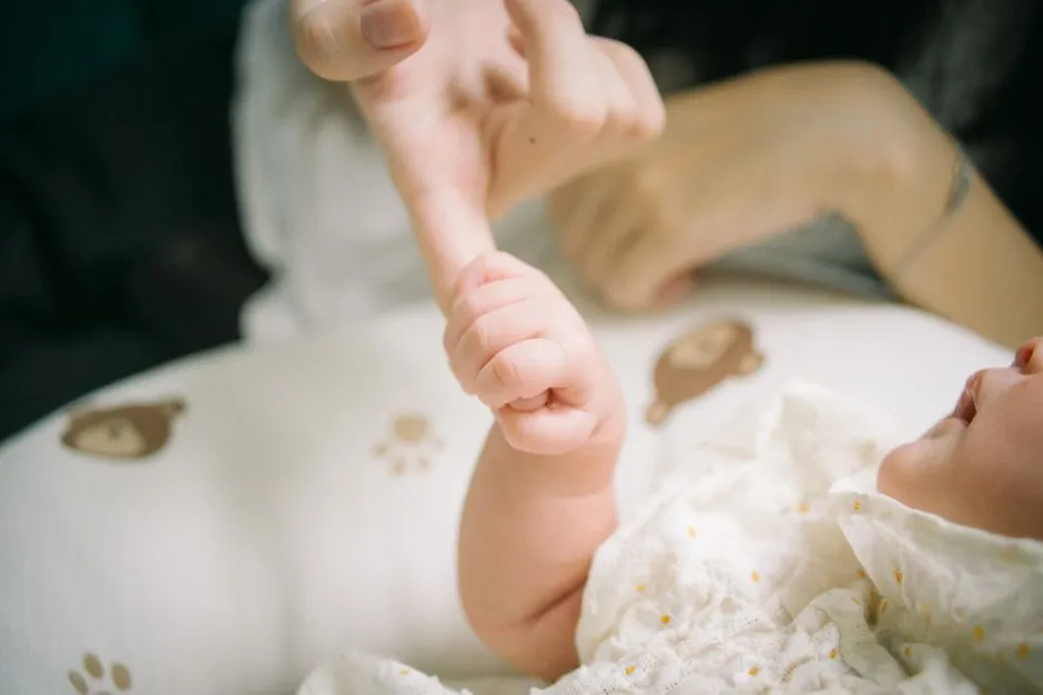 Die winzige Hand eines Neugeborenen umfasst den Finger eines Elternteils