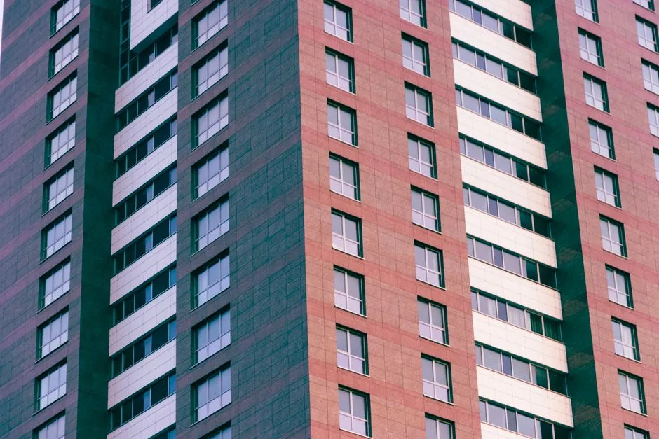 Nahaufnahme der Fassade eines hohen, modernen Wohnblocks mit Fensterreihen