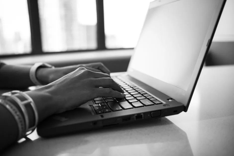 Nahaufnahme von Händen, die auf einer Laptop-Tastatur tippen, ein Online-Antrag wird ausgefüllt
