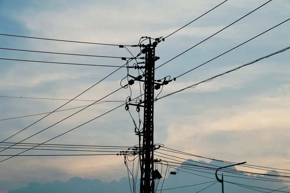 Silhouette eines Strommasts mit Freileitungen vor einem Abendhimmel, keine Menschen, Text oder Logos sichtbar