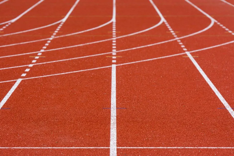 Nahaufnahme leerer roter Laufbahnen auf einer Stadionoberfläche mit weißen Bahnmarkierungen, ohne Menschen, Logos oder lesbare Beschriftung