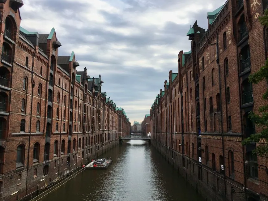 Hamburg'un Speicherstadt semtinde dar bir kanal boyunca sivri üçgen çatılı, dökme demir yaya köprülü, sıra sıra kızıl tuğla Hanseatik depo binaları, hiç insan görünmüyor