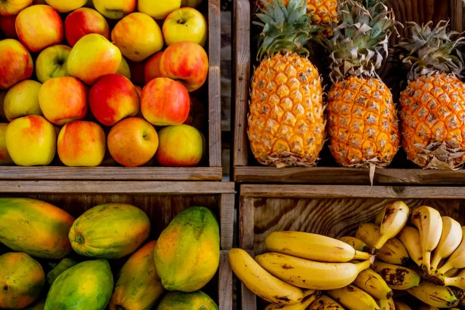 Holzkisten gestapelt mit Äpfeln, Ananas, Papayas und Bananen an einem Obst- und Gemüsestand