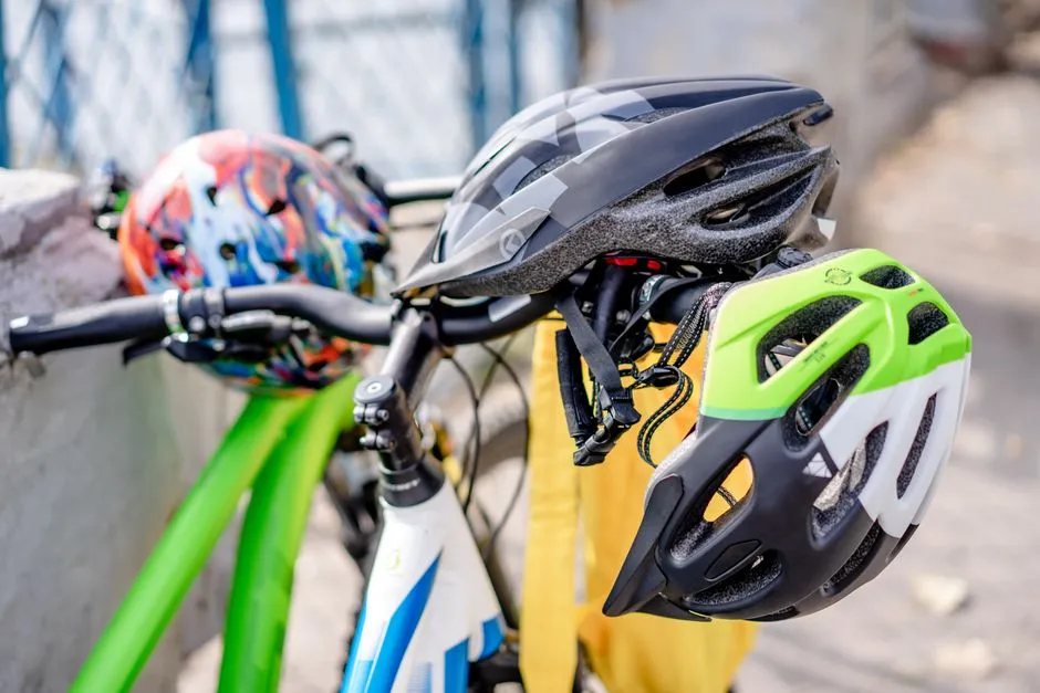 Tres cascos de bicicleta de diferentes colores colgando del manillar de una bicicleta, sin caras ni texto legible visible