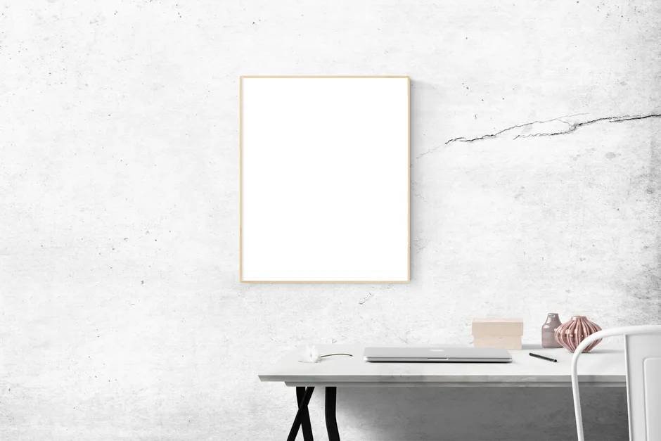 Ein minimalistischer, aufgeräumter Schreibtisch mit einem Laptop und einem leeren gerahmten Bild an der Wand darüber, keine Personen, kein lesbarer Text