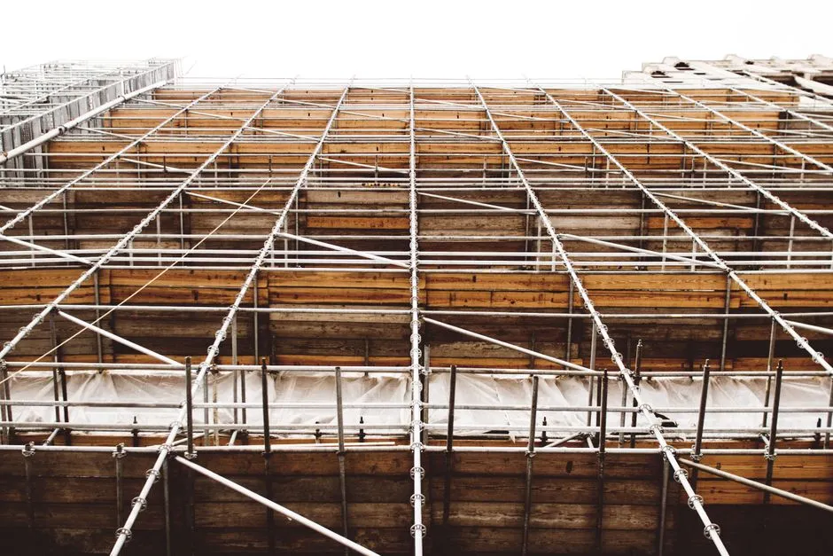 Ein Gerüst aus Metallstangen und Holzplattformen verdeckt die gesamte Höhe einer Hausfassade während einer Sanierung