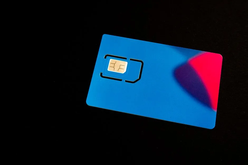 بطاقة SIM مسبقة الدفع زرقاء مستريحة على سطح داكن مع رقاقة التلامس الذهبية ظاهرة