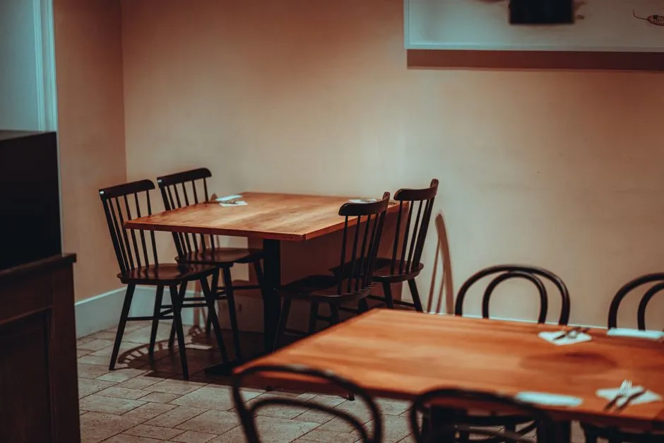 Ahşap masaları ve sandalyeleriyle servise hazırlanmış boş küçük bir restoran salonu, kimse görünmüyor