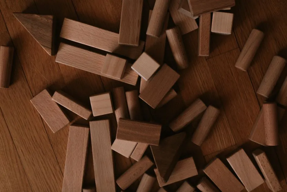 A scattered pile of wooden building blocks of different shapes on a wooden floor, no people, no readable text