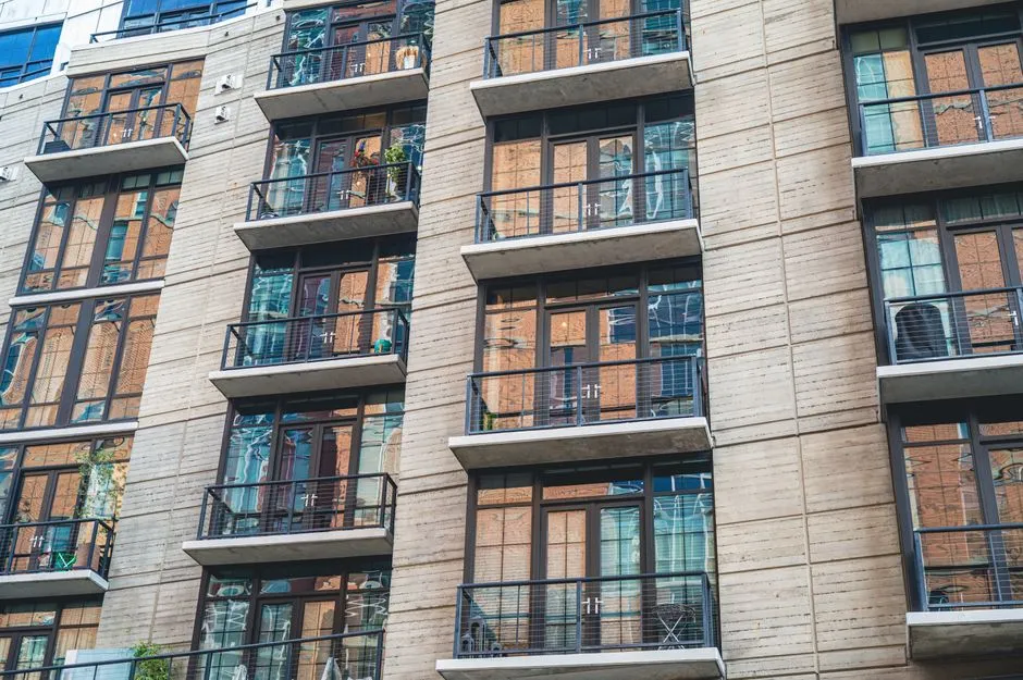 Eine moderne Wohnhausfassade mit Reihen von Glasbalkonen und Betontrennwänden, keine Personen oder lesbare Beschilderung sichtbar