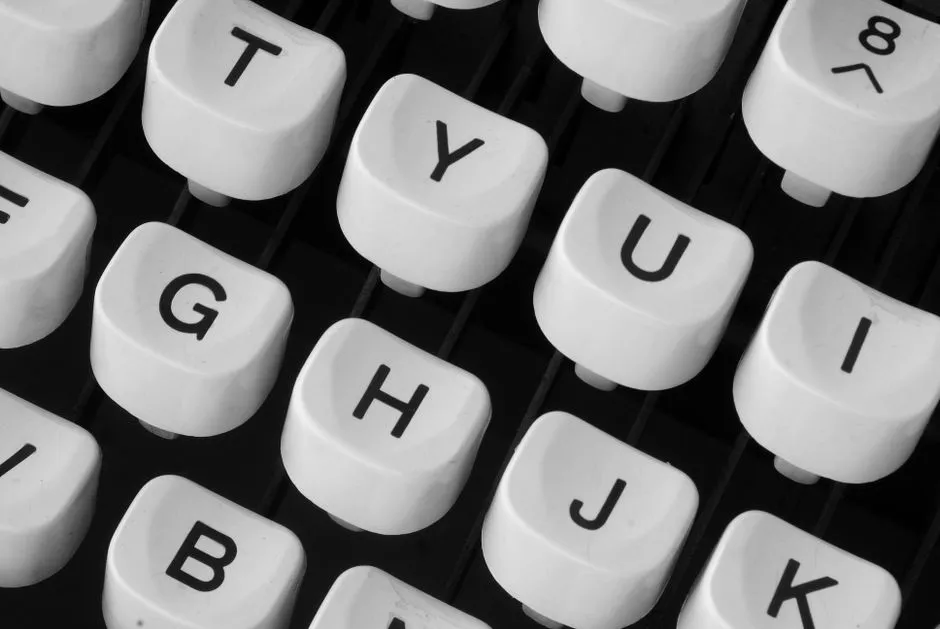 Nahaufnahme von Tasten einer altmodischen Schreibmaschine, in überlappenden diagonalen Reihen angeordnet, jede runde weiße Taste zeigt einen einzelnen schwarzen Buchstaben