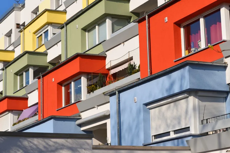 Bunte moderne Wohnhausfassaden mit Balkonen, dicht aneinandergereiht entlang einer deutschen Wohnstraße