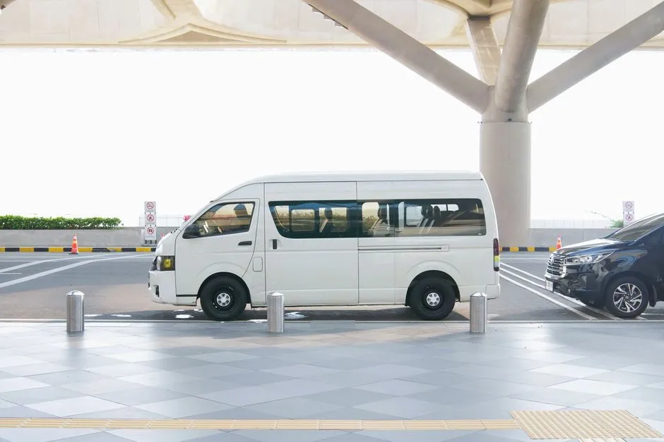 Kapalı bir terminal yapısı altında park edilmiş sade beyaz bir minibüs, kimse ya da tanımlayıcı bir tabela görünmüyor