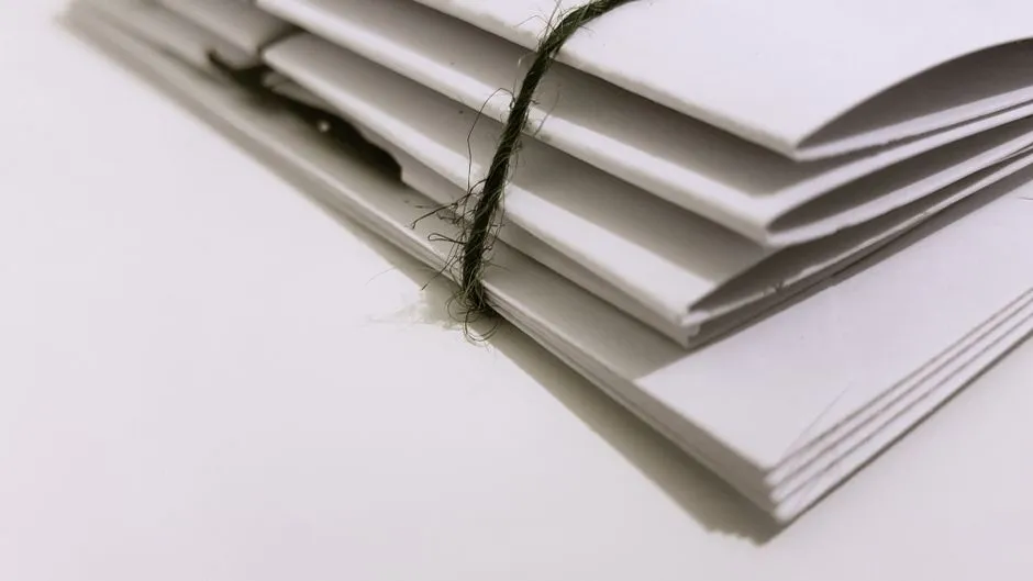 A stack of white paper envelopes bound with string, viewed at a close angle