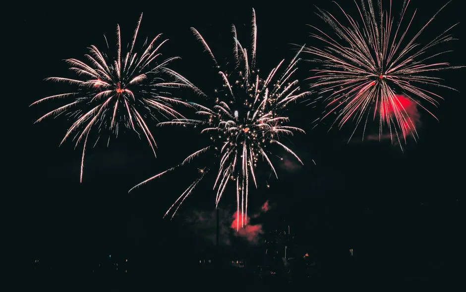 Ein großes Feuerwerk explodiert am dunklen Nachthimmel, mehrere helle Sternexplosionen mit nachlaufenden Funken