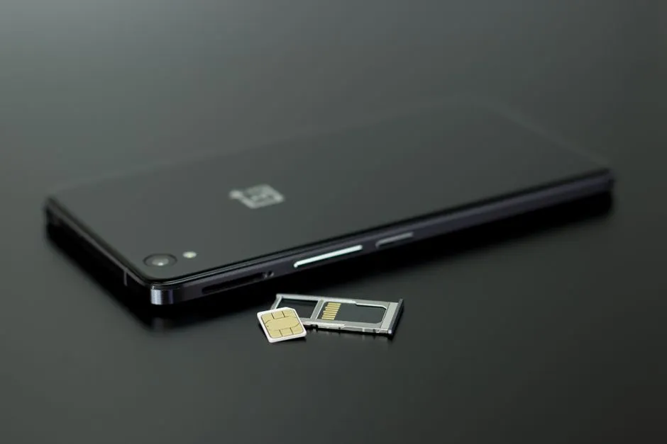Eine SIM-Karte und ihr Einschub neben einem Smartphone auf einem dunklen Tisch, bereit zur Aktivierung