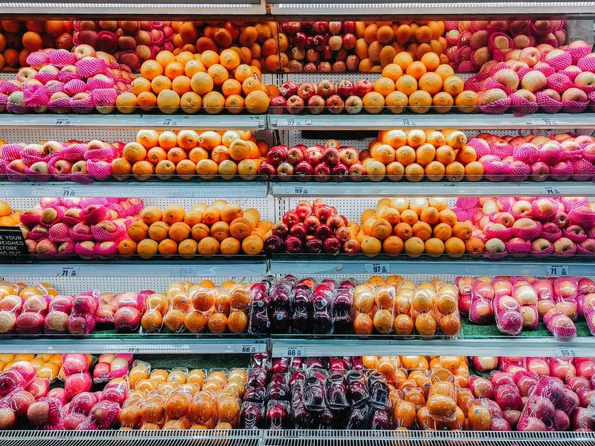 Shelves of fresh apples and oranges displayed in a grocery store produce section