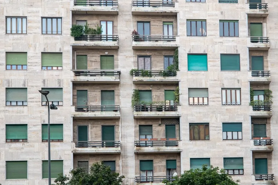 Die Fassade eines mehrstöckigen Wohnhauses mit Reihen von Balkonen und Rollläden