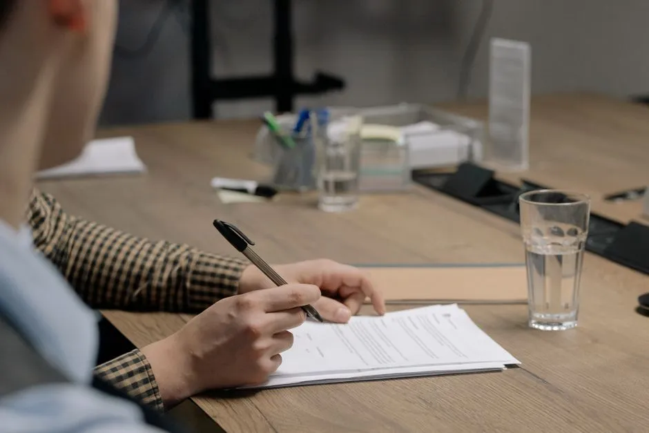Eine Person unterschreibt ein Arbeitsvertragsdokument an einem Bürotisch