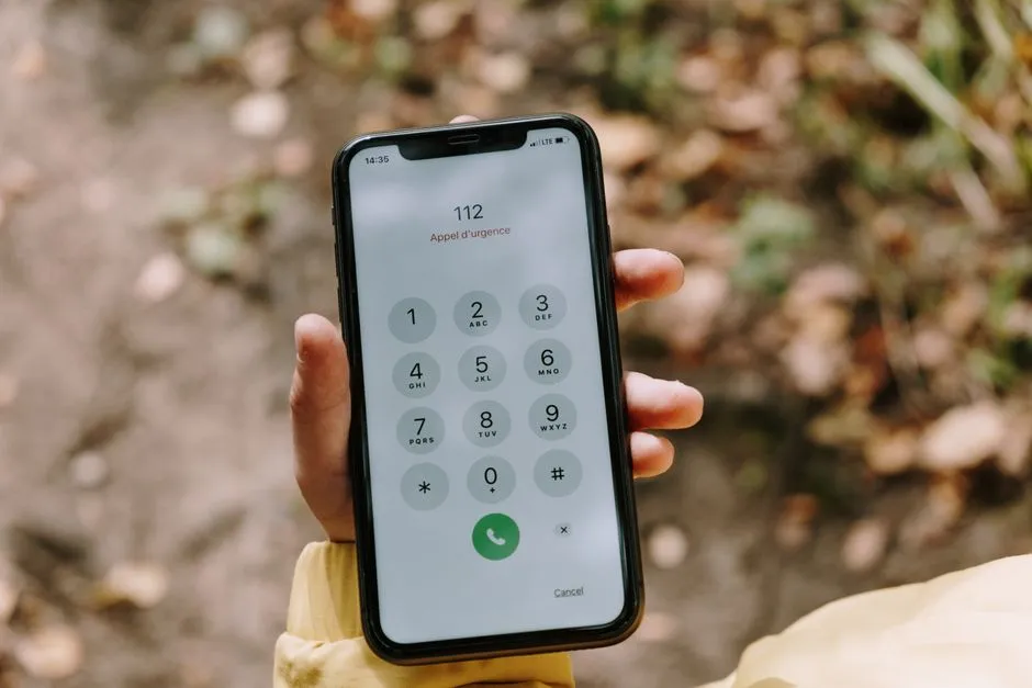 Eine Hand hält ein Smartphone mit einem Notruf-Wählbildschirm, auf dem die Nummer 112 zu sehen ist