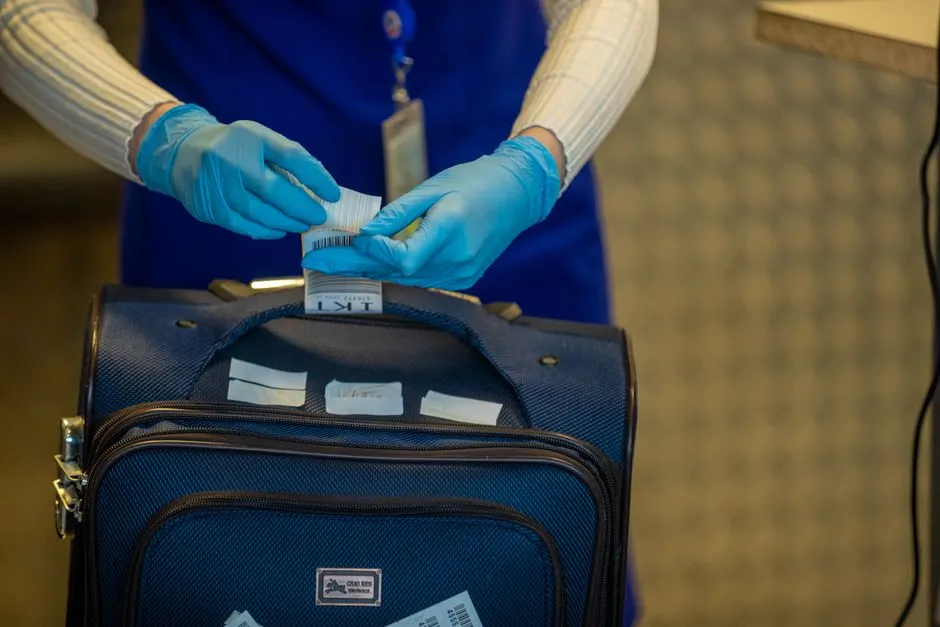 A staff member tagging a suitcase with an inspection label at a checkpoint