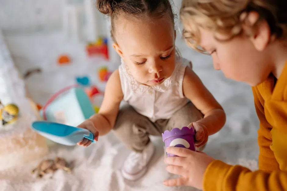 Zwei kleine Kinder spielen zusammen mit Spielzeug in einer hellen Kita-Umgebung